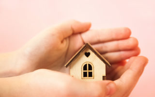 Bien dans mon environnement, des mains tenant une maison en bois miniature