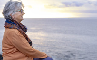 Bien être, bien vieillir, retraitée assise, regardant la mer au loin.