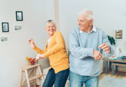 Bien avec mes proches, couple de retraité heureux qui dance dans un salon